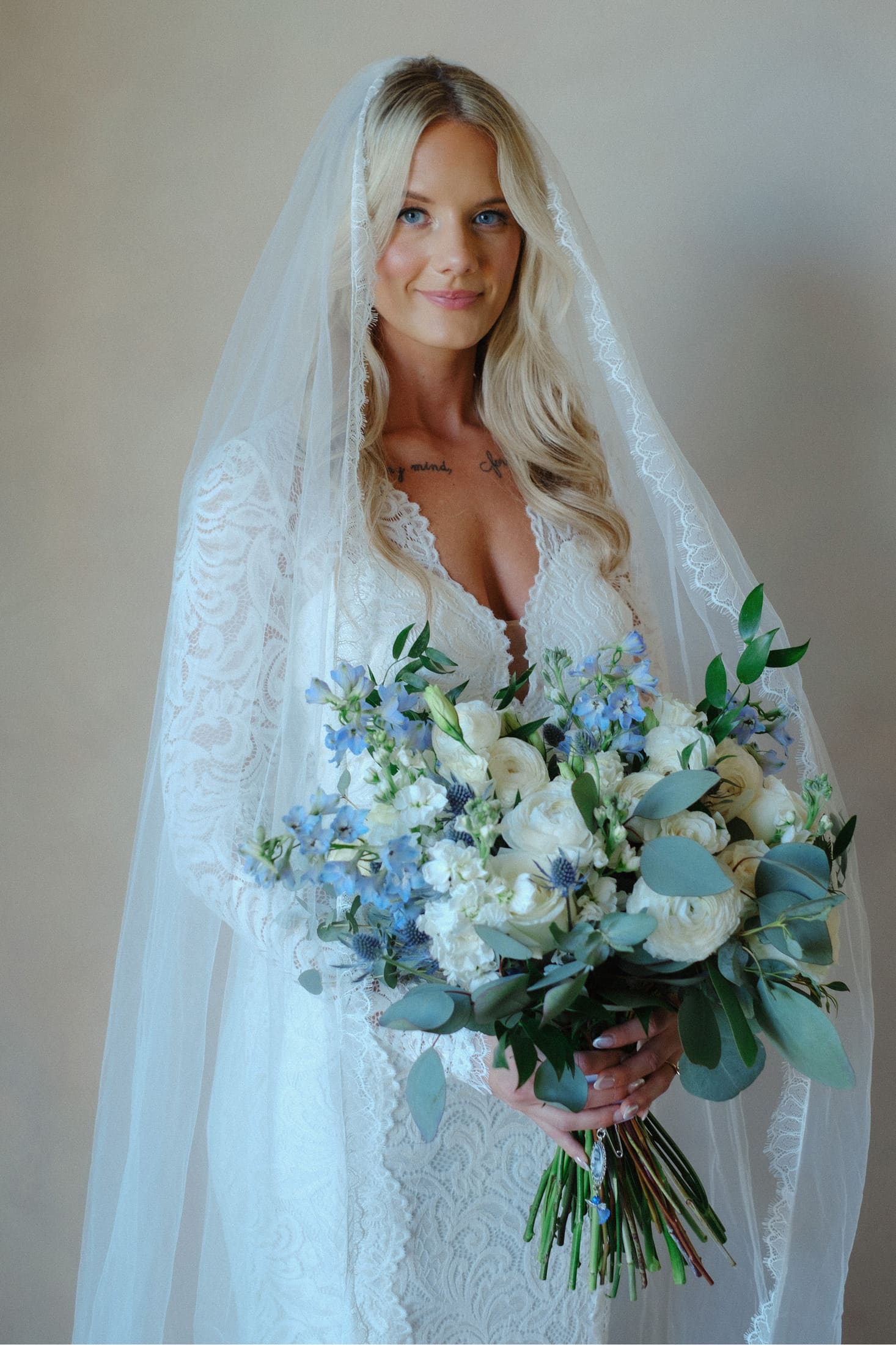 Bride in a finished wedding look with soft waves, veil, and bouquet